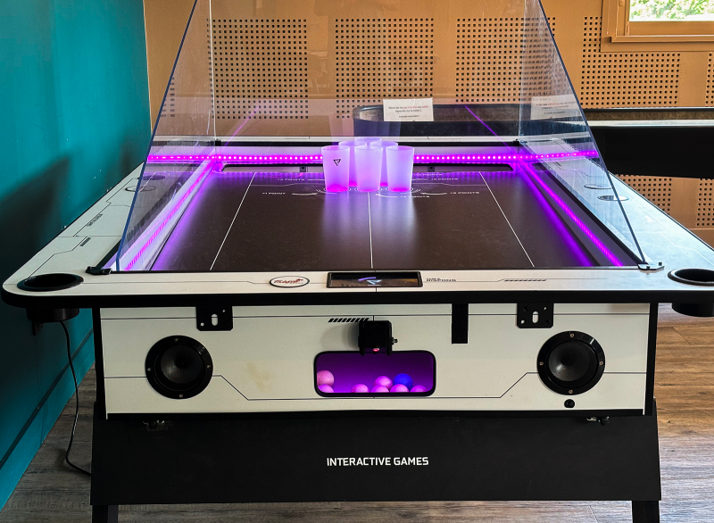 Table de beer pong avec gobelets et balles dans un bar à jeux à Montpellier.