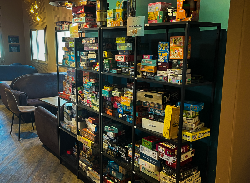 Collection de jeux de société sur une étagère dans un bar.